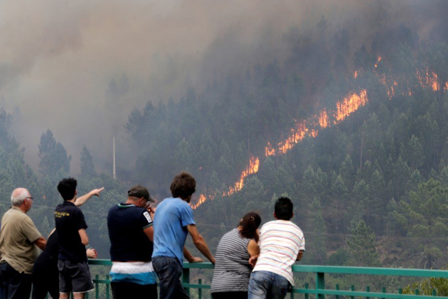 Pessoas olham para o fogo que consome a floresta em Pedrogão Grande, em Portugal neste domingo 18 de junho de 2017