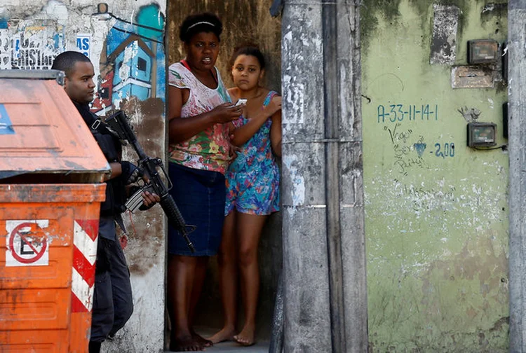 CIDADE DE DEUS: moradores observam policial; comunidade foi ocupada após a queda de helicóptero que matou quatro PMs / Ricardo Moraes/ Reuters