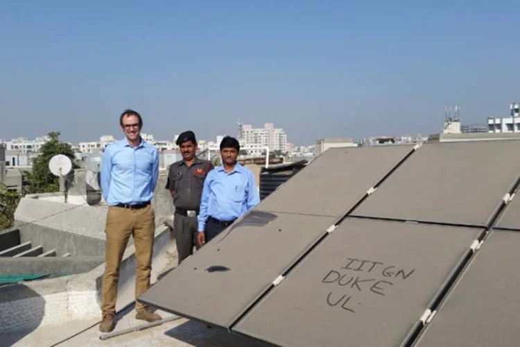 Michael Bergin (à esq.), ao lado do colega indiano Chinmay Ghoroi (à dir.) e os empoeirados  painéis solares da IITGN. (Duke University/Divulgação)