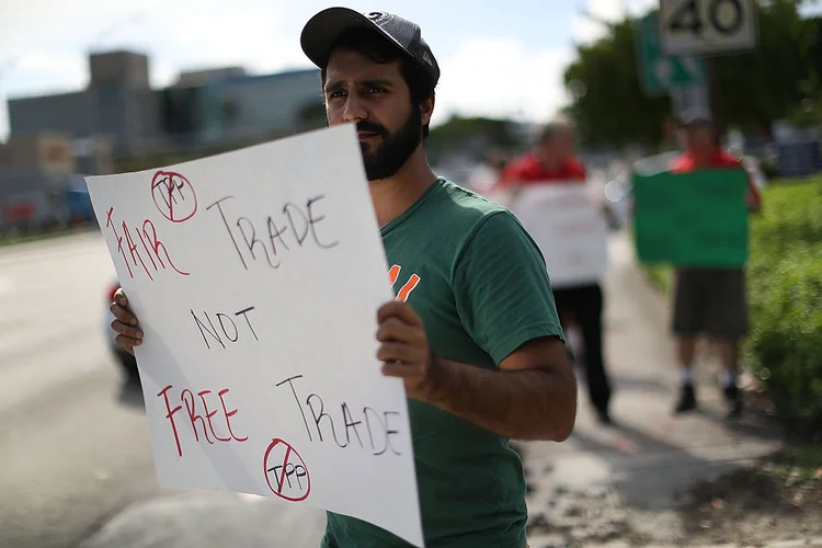 ESTADOS UNIDOS: manifestante segura cartaz com os dizeres &#8220;Comércio justo, não livre comércio&#8221;, na Flórida, em protesto contra o TPP; Donald Trump decidiu por retirar o país do acordo / Joe Raedle/Getty Images