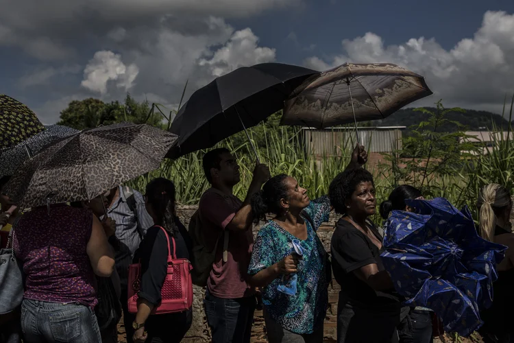 Pessoas com guarda-chuva em fila de emprego no Rio de Janeiro (Dado Galdieri/Bloomberg)