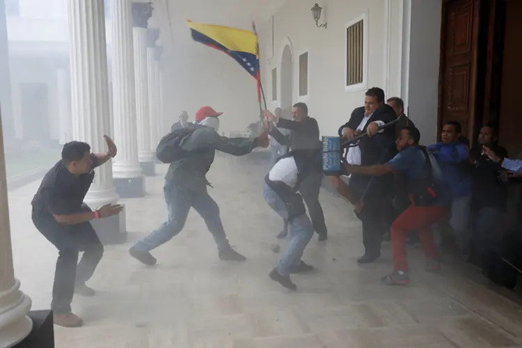 Dezenas de pessoas com pedaços de pau nas mãos e vestidas de vermelho, tomaram os jardins do Palácio Legislativo e detonaram rojões (Andres Martinez Casares/Reuters)