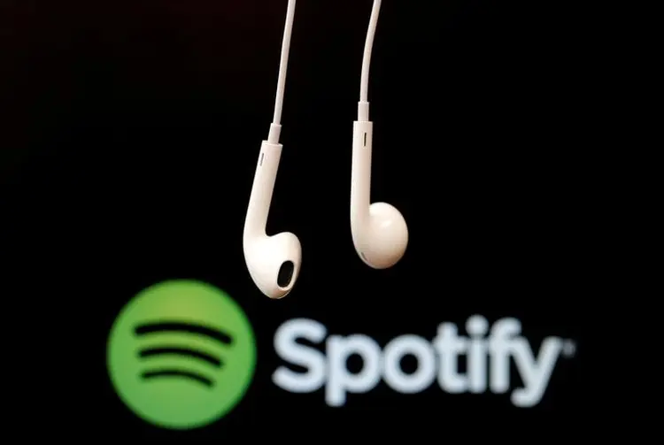 Fones de ouvido diante do logo do Spotify (Christian Hartmann/Reuters)