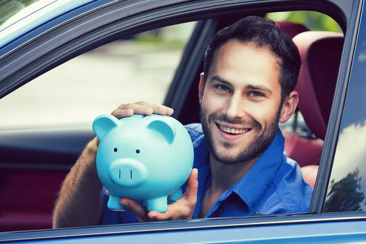 Homem segura cofre de porquinho em carro:: saiba economizar combustível em tempo de alta dos preços (SIphotography/Thinkstock)