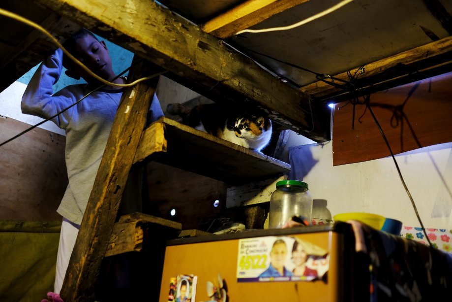 Brian, filho da catadora Fabiana da Silva com seu gato, dentro de casa