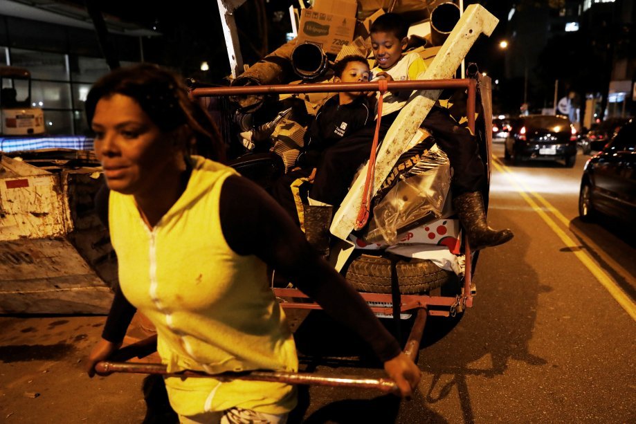 Fabiana da Silva, 38, trabalhando como catadora, acompanhada dos seus filhos Brian e Jean, em São Paulo