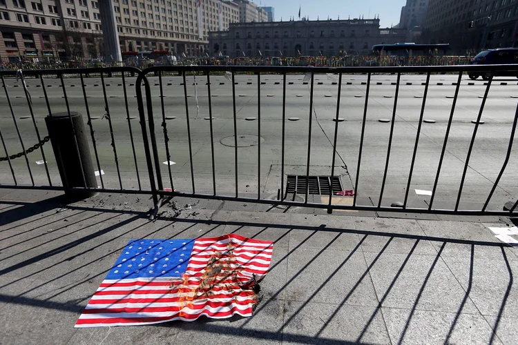 Santiago: bandeira americana é queimada em protesto na capital do Chile, durante visita do vice-presidente Mike Pence (Carlos Vera/Reuters)