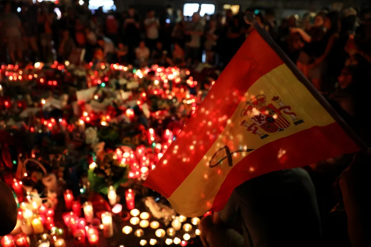 Pessoa segura bandeira da Espanha em homenagem às vítimas do atentado em Barcelona: mortos no atropelamento identificados até o momento são quatro espanhóis, dois portugueses, um italiano e um americano (Susana Vera/Reuters)