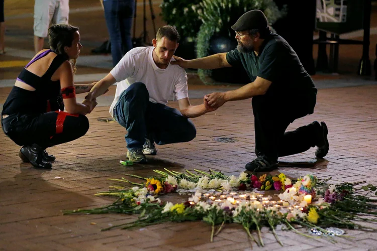 Homem é apoiado por policiais ao prestar sua homenagem a amigo feriado em atropelamento em Charlottesville (Jim Bourg/Reuters)