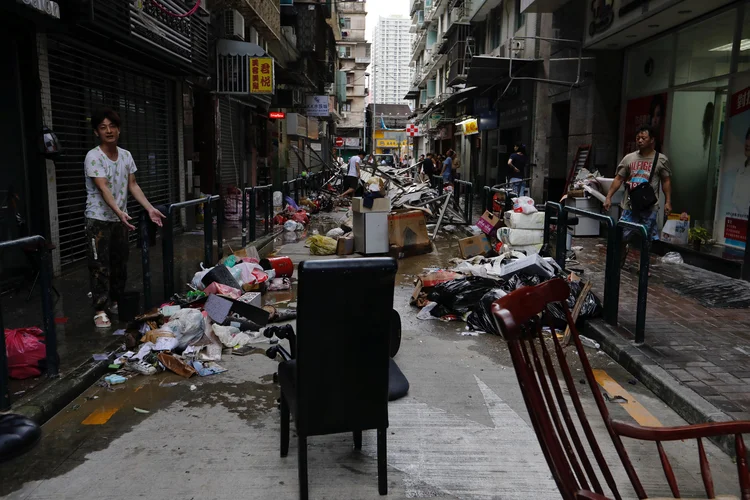 Homem em frente de loja atingida pelo furacão Hato, em Macau (China): mais de 410 mil pessoas foram afetadas pelas chuvas na província de Yunnan (Tyrone Siu/Reuters)