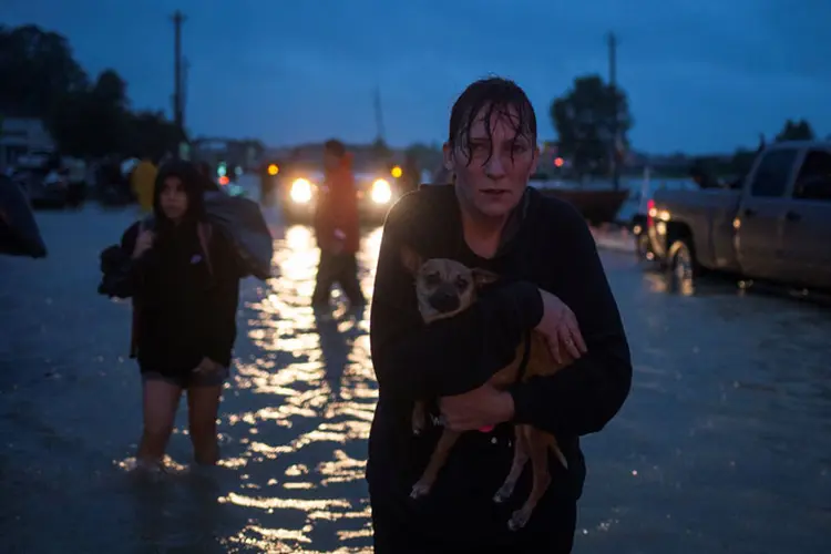 Mulher foge com seu cachorro do Texas após passagem do furacão Harvey (Adrees Latif/Reuters)