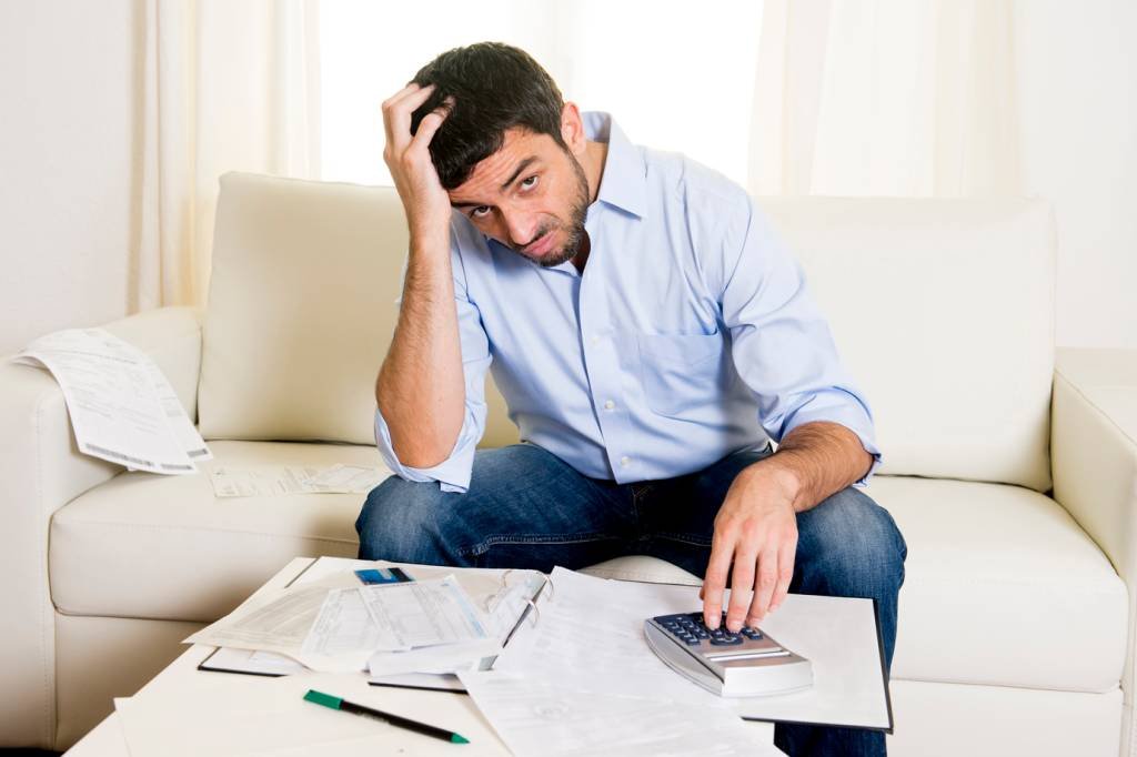 Homem preocupado com contas: empréstimos com e sem garantia devem ser declarados de forma diferente (OcusFocus/Thinkstock)