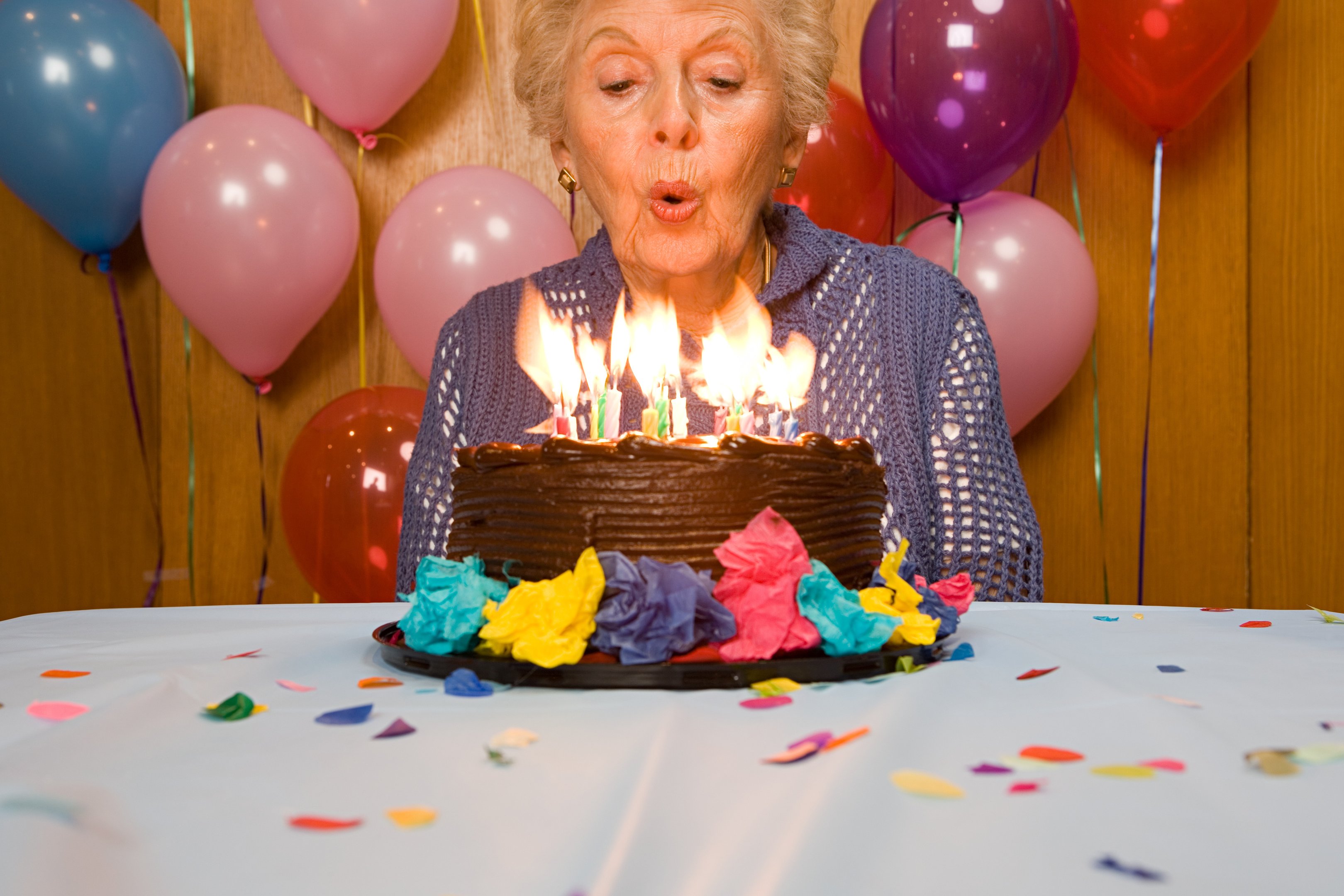 Mulher idosa soprando vela de bolo de aniversário