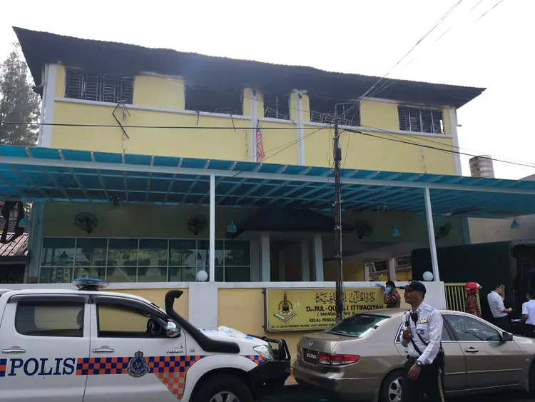 Polícia e bombeiros na frente de escola onde houve incêndio: o fogo teria começado com um curto-circuito ou em um aparelho de combate a mosquitos (A. Ananthalakshmi/Reuters)