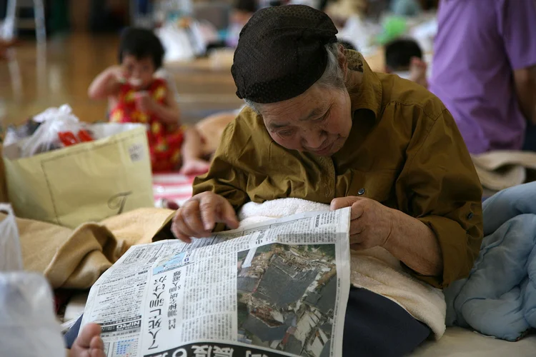 Idosa lê jornal no Japão (Koichi Kamoshida/Getty Images)