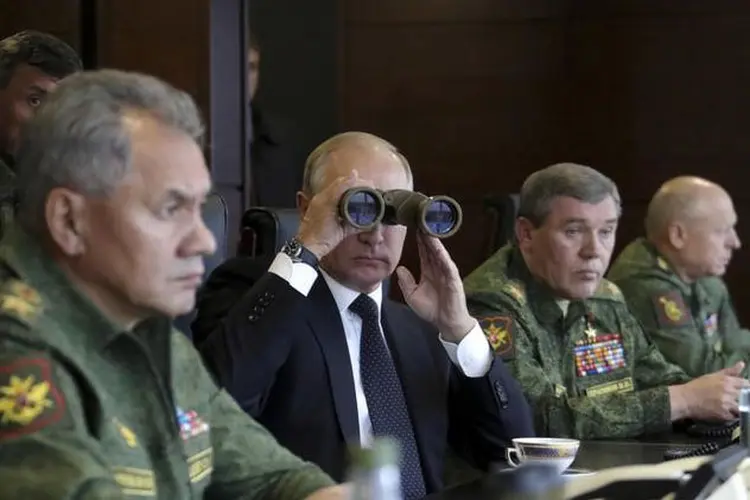 Putin: o presidente russo usou binóculos para poder ver o conflito simulado se desenrolando diante de seus olhos sob uma garoa fria (Sputnik/Mikhail Klimentyev/Kremlin/Reuters)