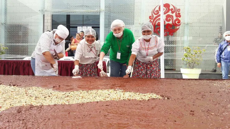 Produtores ao lado da barra de chocolate gigante: barra é feita com 70% de cacau puro e o doce mede 21 metros quadrados. (Devida Perú/ Twitter/Divulgação)
