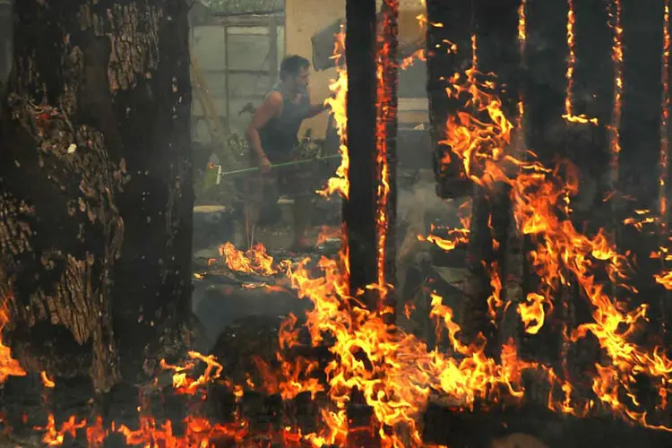 Homem tenta salvar pertences de sua casa tomada por chamas, em 9 de outubro de 2017. 