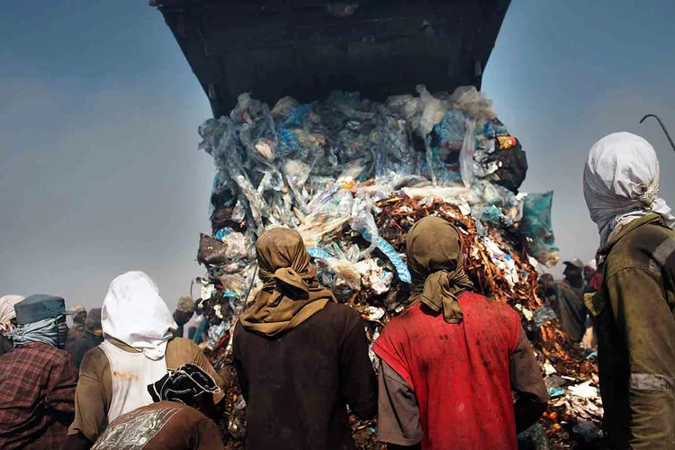 Pessoas observam um caminhão despejar lixo nos arredores de Porto Príncipe, no Haiti. (Spencer Platt/Getty Images)