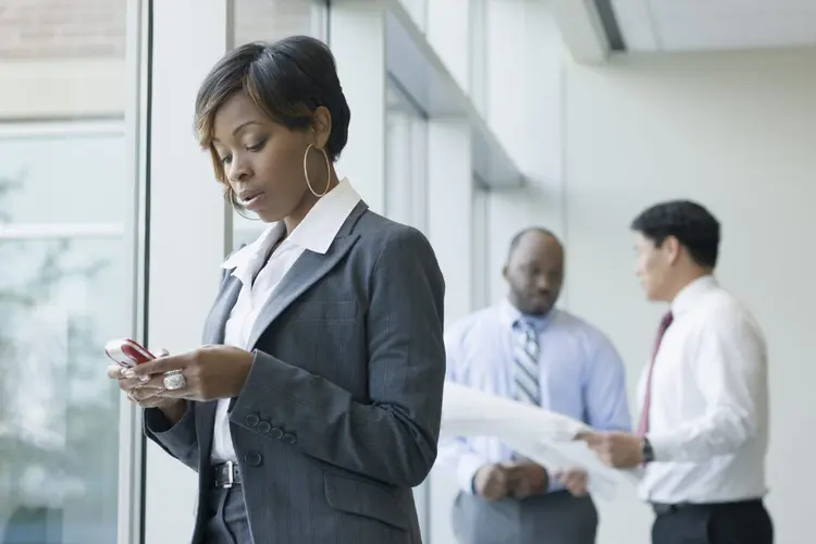 Mulher usando o celular durante o trabalho (Terry Vine/Thinkstock)