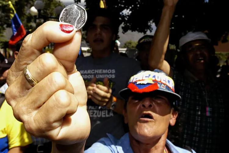 Venezuelana segura moeda em protesto em Caracas (Susana Gonzalez/Getty Images)