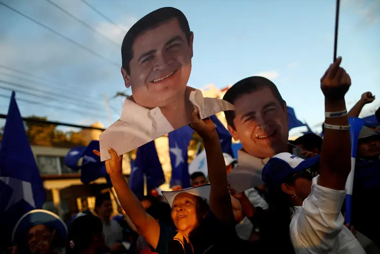 Eleitores do presidente de Honduras, Juan Orlando Hernández, seguram cartazes em apoio ao candidato (Edgard Garrido/Reuters)