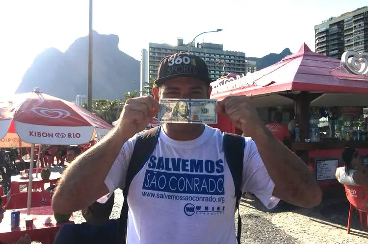 Marcello Farias, da página Salvemos São Conrado, mostra nota de 100 dólares que ganhou de recompensa por devolver carteira (reprod/Reprodução)