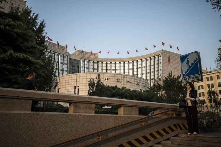 Mulher com telefone celular na sede do PBOC, banco central chinês, em Beijing (Qilai Shen/Bloomberg)