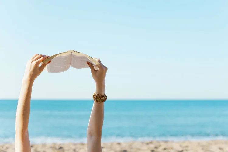 Mulher lê na praia: que tal aproveitar os dias de folga para colocar em dia a leitura? (eternalcreative/Thinkstock)