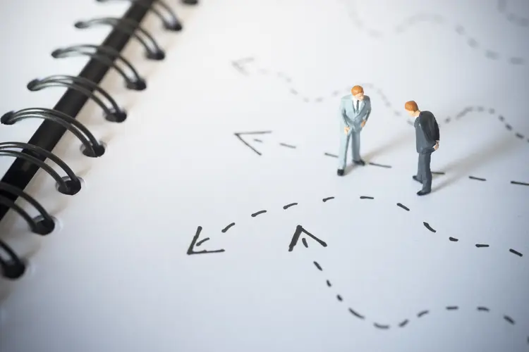 Business decision concept. Businessmen standing and giving advice with arrow pathway choice. (TanawatPontchour/Thinkstock)