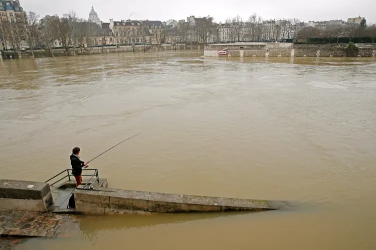 Homem pesca no Rio Sena: barcos turísticos foram fechados devido à altura das águas (Pascal Rossignol/Reuters)