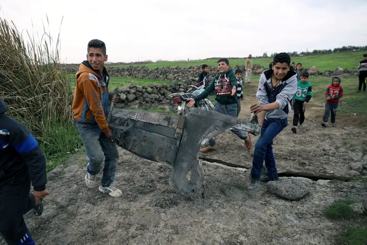 Crianças carregam destroços de um caça israelense na Síria, em 10/02/2018 (REUTERS/ Alaa al Faqir/Reuters)