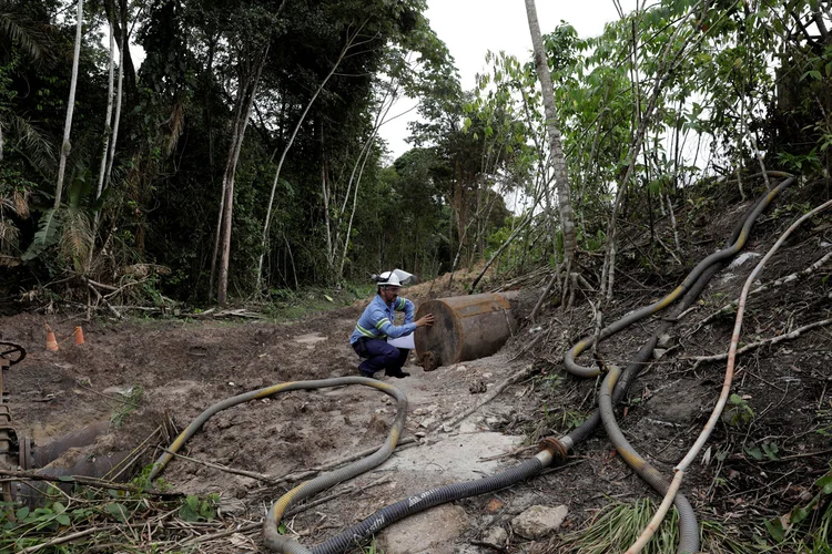 Homem mostra cano que termina no meio ambiente da empresa Norsk Hydro ASA, em Barcarena, no Pará, dia 05/03/2018 (Ricardo Moraes/Reuters)