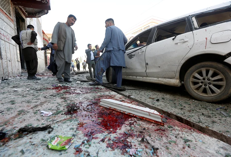 Homens afegãos inspecionam o local onde um terrorista explodiu uma bomba, em cartório eleitoral de Cabul, Afeganistão (Omar Sobhani/Reuters)