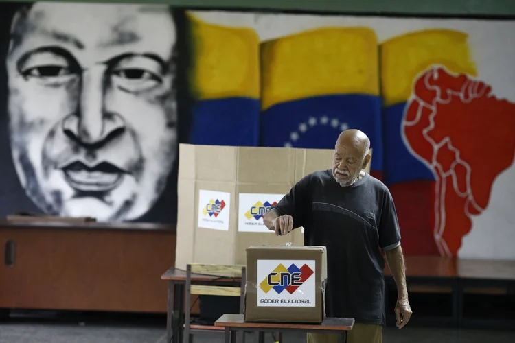 Eleição na Venezuela: Cidadão vota em Caracas em frente à imagem do ex-presidente Hugo Chavez, morto em 2013 (Marco Bello/Reuters)