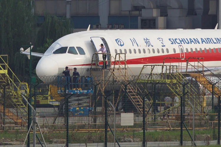 Funcionários da Sichuan Airlines inspecionam aeronave cujo para-brisa estourou em pleno voo (Stringer/Reuters)