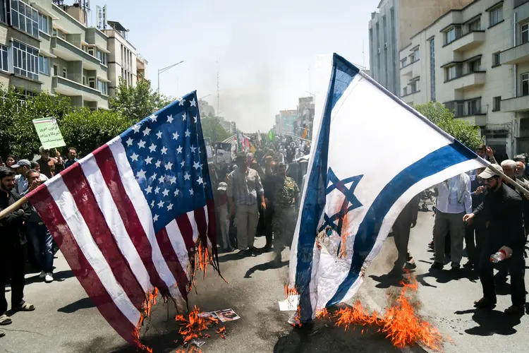 Bandeiras dos EUA e Israel sendo queimadas no Irã: país havia prometido retaliações (Tasnim News Agency/Reuters)