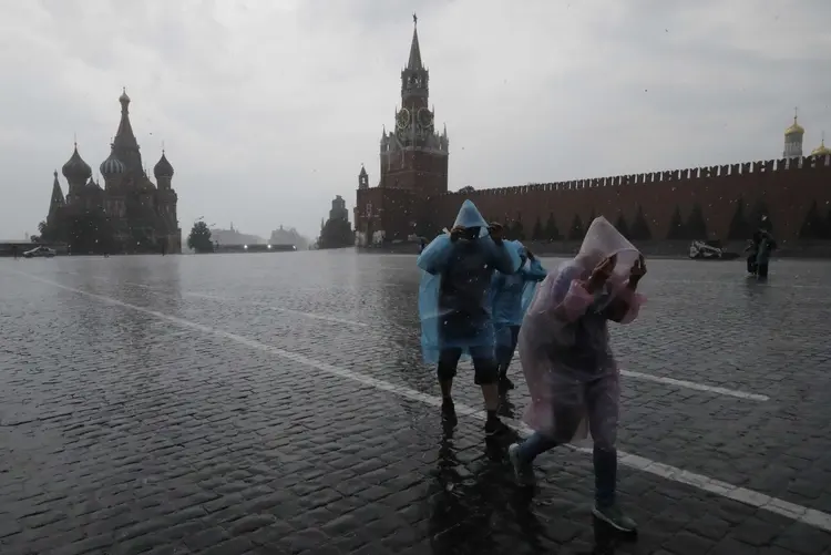 Pessoas se protegem de temporal na Praça Vermelha em Moscou, na Rússia (Sergei Karpukhin/Reuters)