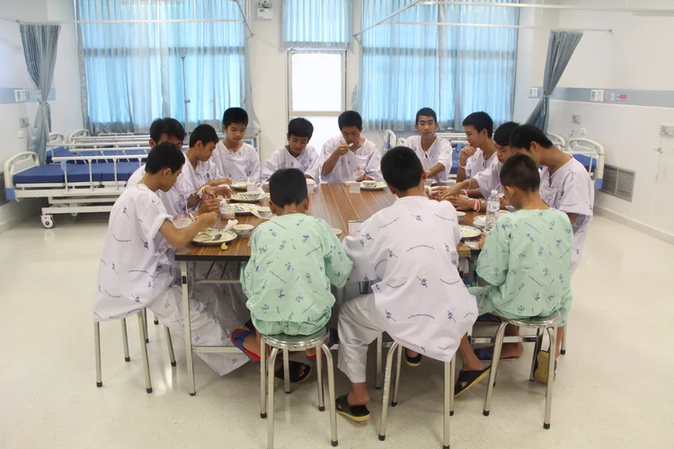 Os 12 membros do time de futebol da Thailândia e seu treinador posam ao lado de uma figura de Samarn Kunan, mergulhador voluntário que morreu durante o resgate, no hospital de Chiang Rai Prachanukroh  (Reuters/Reuters)