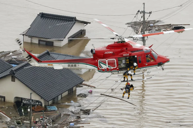 Visão aérea mostra residente local sendo resgatado de casa submersa em Kurashiki (Kyodo/Reuters)