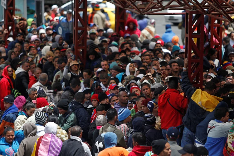 Migrantes venezuelanos esperam para registrar saída da Colômbia para entrar no Equador.  (Daniel Tapia/Reuters)