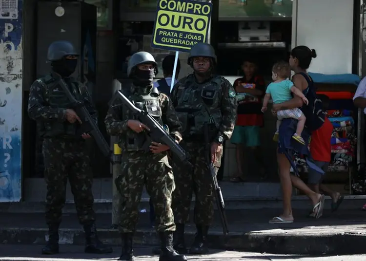 Intervenção: moradores passam por soldados armados durante operação contra tráfico de drogas na Rocinha, no dia 26 de julho; intervenção completa seis meses, sem cumprir promessas (Pilar Olivares/Reuters)