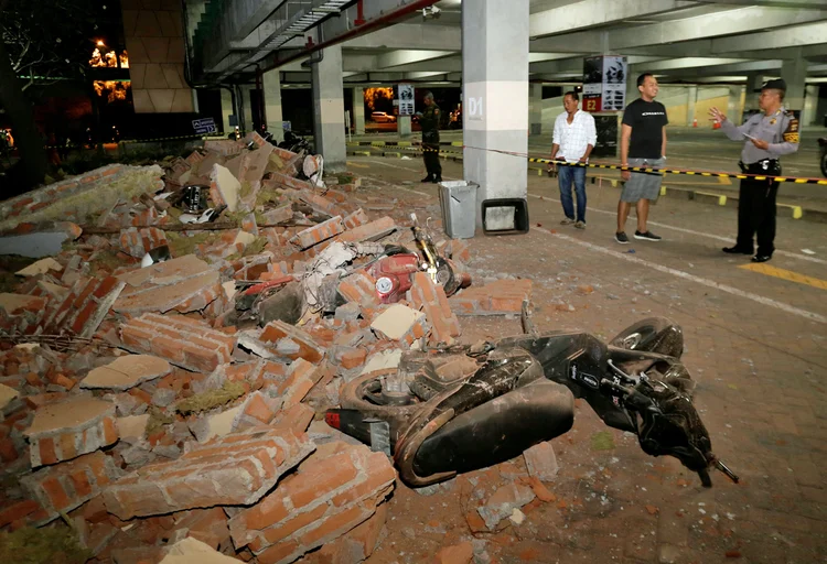 Policial examina escombros que caíram e acertaram motos estacionadas em shopping de Kuta, em Bali, após o terremoto (Johannes P. Christo/Reuters)