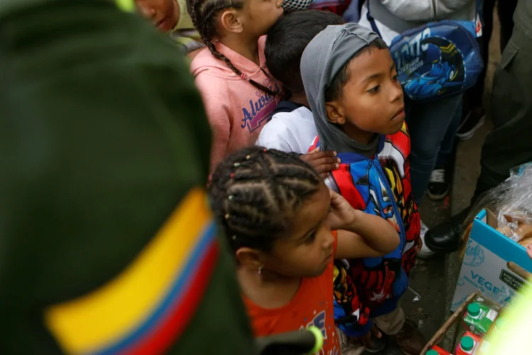 Crise econômica: filhos de imigrantes venezuelanos fazem fila para receber comida em um acampamento improvisado em Bogotá (Luisa Gonzalez/Reuters)