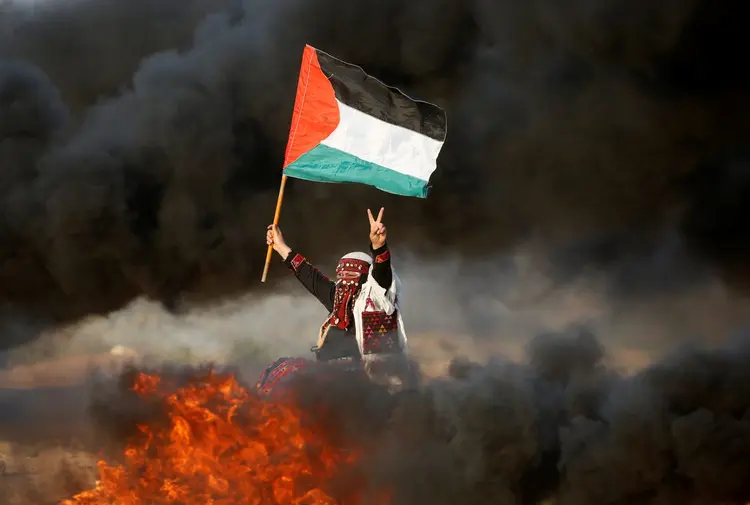 MULHER ERGUE BANDEIRA PALESTINA: Sete palestinos, entre eles dois adolescentes de 12 e 14 anos, morreram nesta sexta-feira (Mohammed Salem/Reuters)