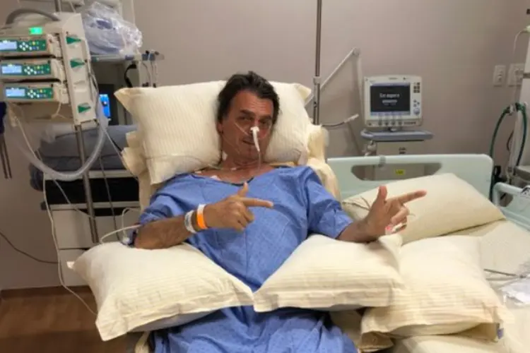 Jair Bolsonaro no hospital, fazendo gesto com as mãos que simula armas: Bolsonaro é um defensor da posse de armas de fogo como instrumento de defesa pessoal (@FlavioBolsonaro/Twitter/Reprodução)