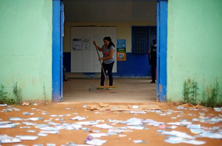 Mulher limpa propaganda eleitoral de chão para a votação em Brasília, dia 07/10/2018 (Adriano Machado/Reuters)