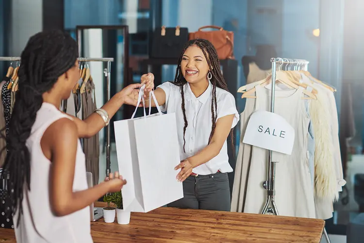 Cropped shot of a young store owner handing a parcel to a customer over the counter (PeopleImages/iStockphoto)