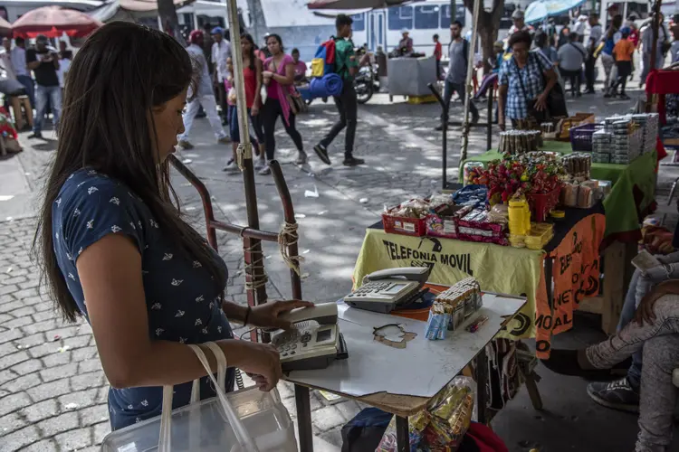 Mulher em estande de rua para comunicação, onde telefones alugados por minuto em Caracas (Carlos Becerra/Bloomberg)