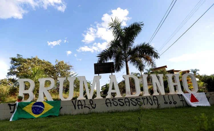 Brumadinho: grafite na entrada da cidade mineira, onde se lê "Vale assassina", visto entre a bandeira nacional brasileira e a bandeira do estado de Minas Gerais (Adriano Machado/Reuters)